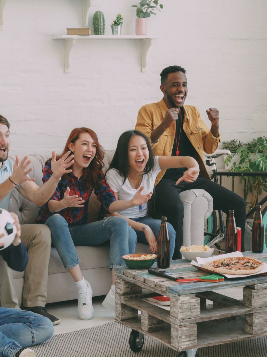 Friends cheering while watching a football match together