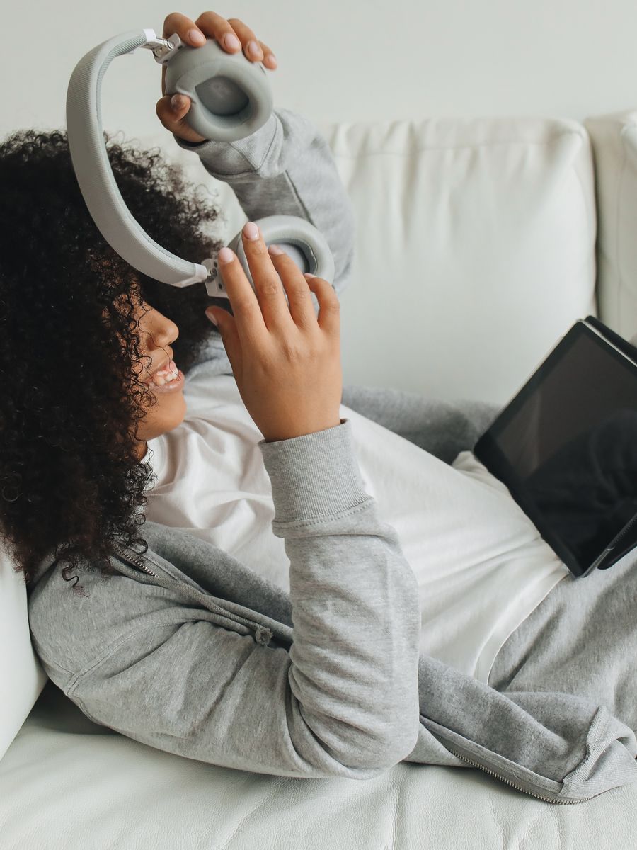 A woman relaxing on the couch with headphones and a phone